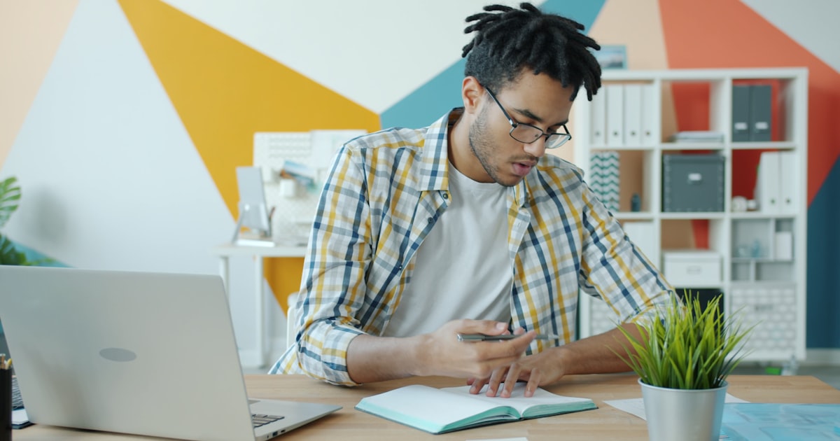 Man working at a desk with laptop and notebook.