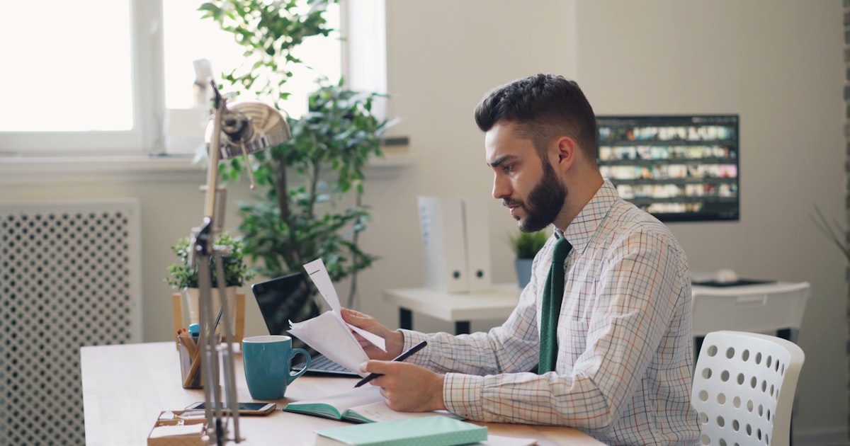 a man sitting at a desk with a laptop and papers