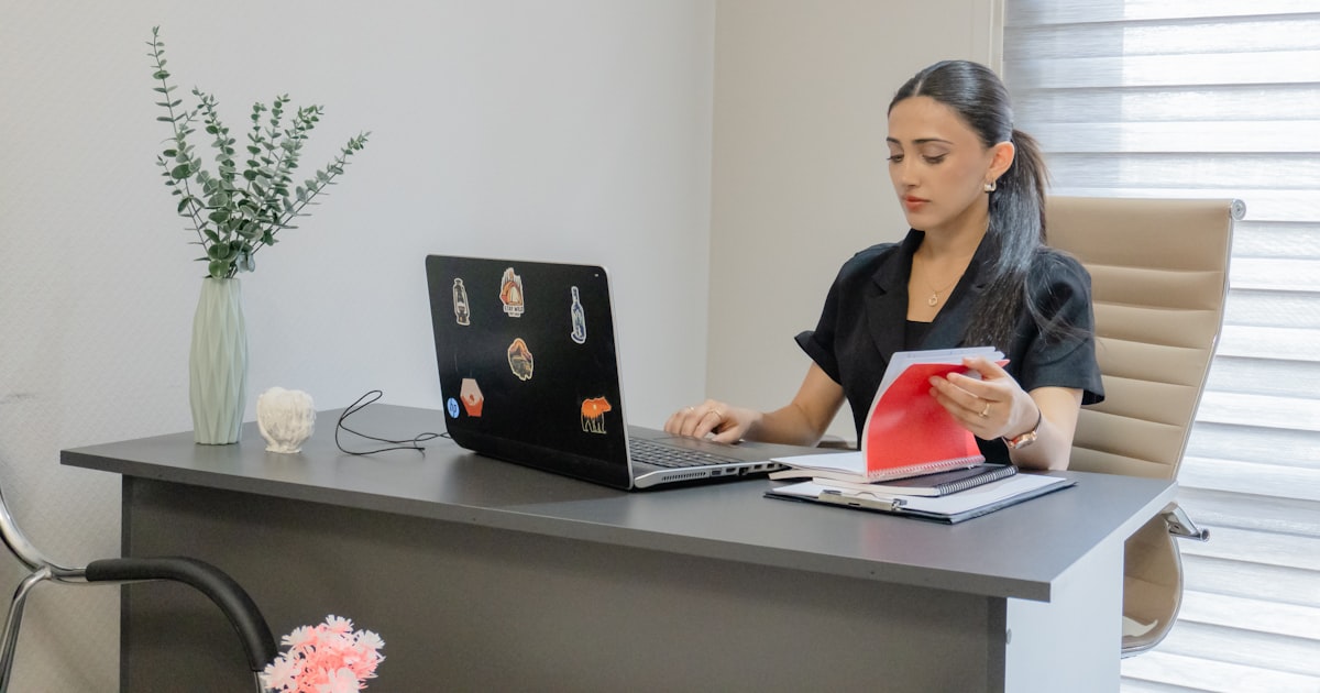 Woman working on a laptop at a desk.